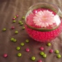 Bolvaasje met roze gelparels zachtroze gerbera en beregras versierd rondom met gepersonaliseerde m&m's